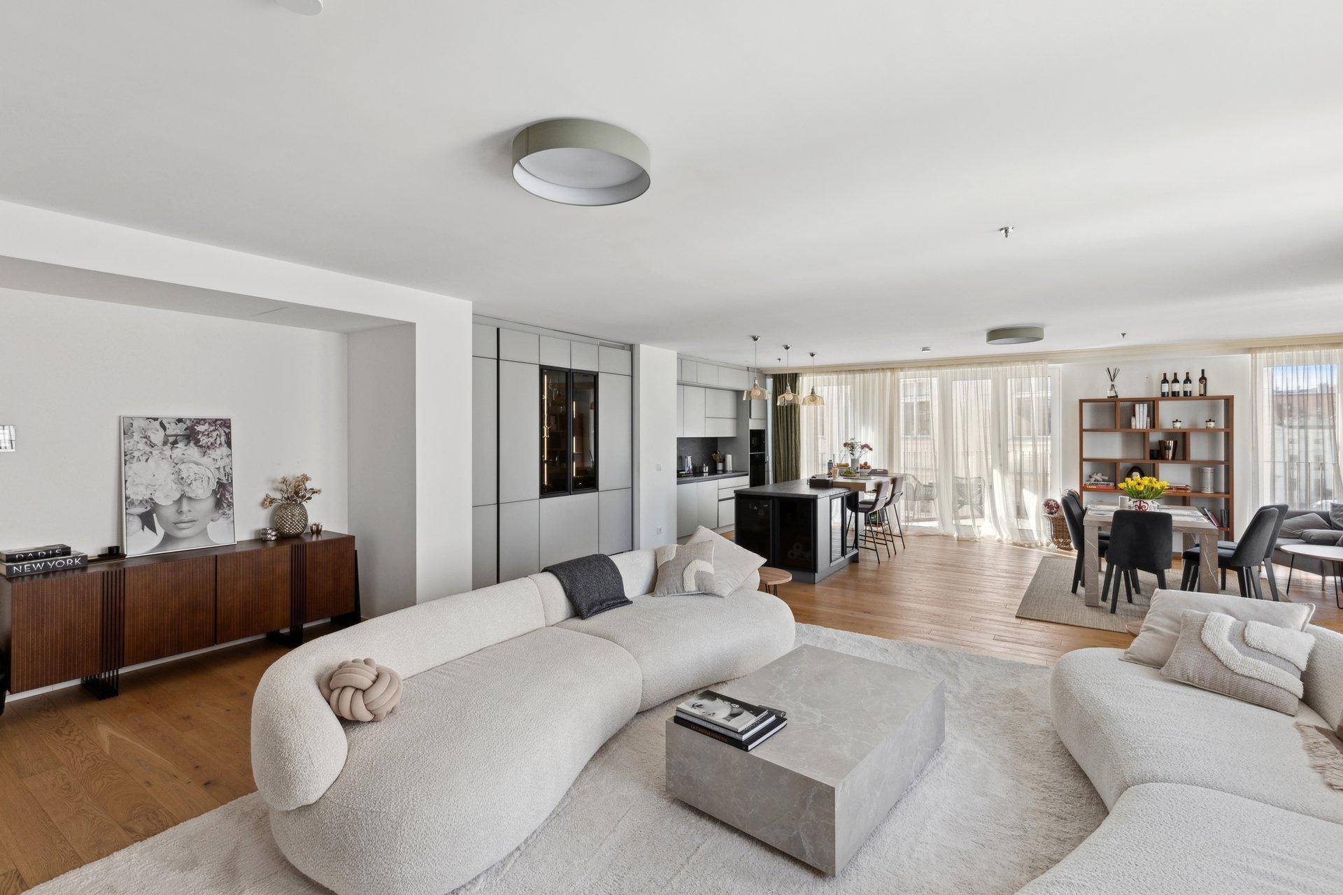 Heller Wohnbereich mit stilvollen Sofas, integrierter Küche und Essbereich.