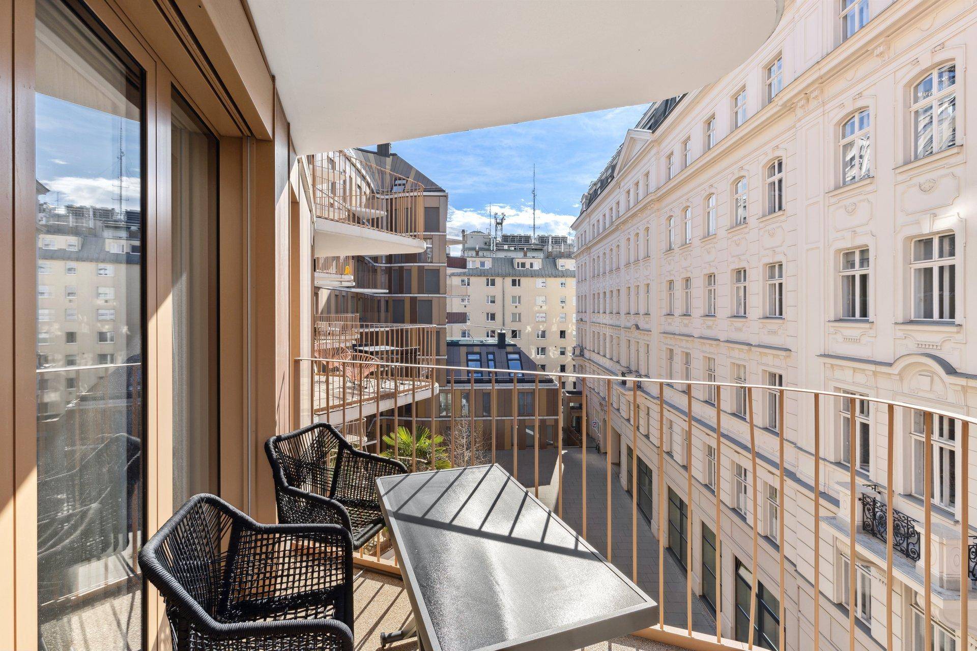 Möblierter Balkon mit Blick auf die umliegenden Gebäude und die Stadt.
