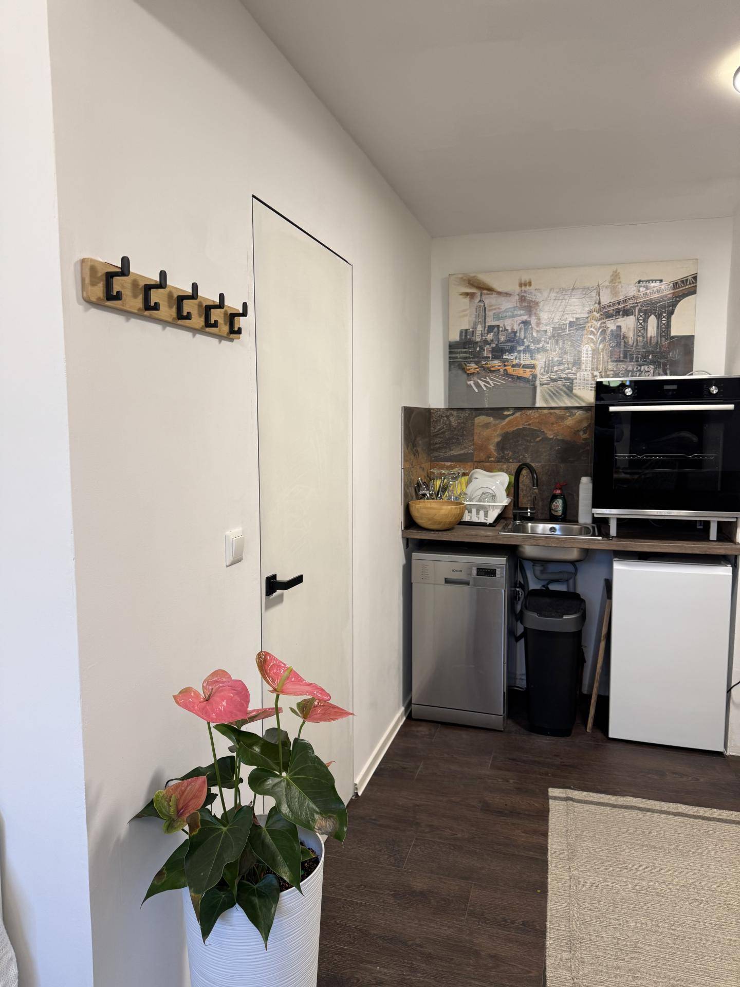 Kompakte Küchenzeile mit Spülmaschine, Backofen und Kühlschrank in einem Wohnbereich.