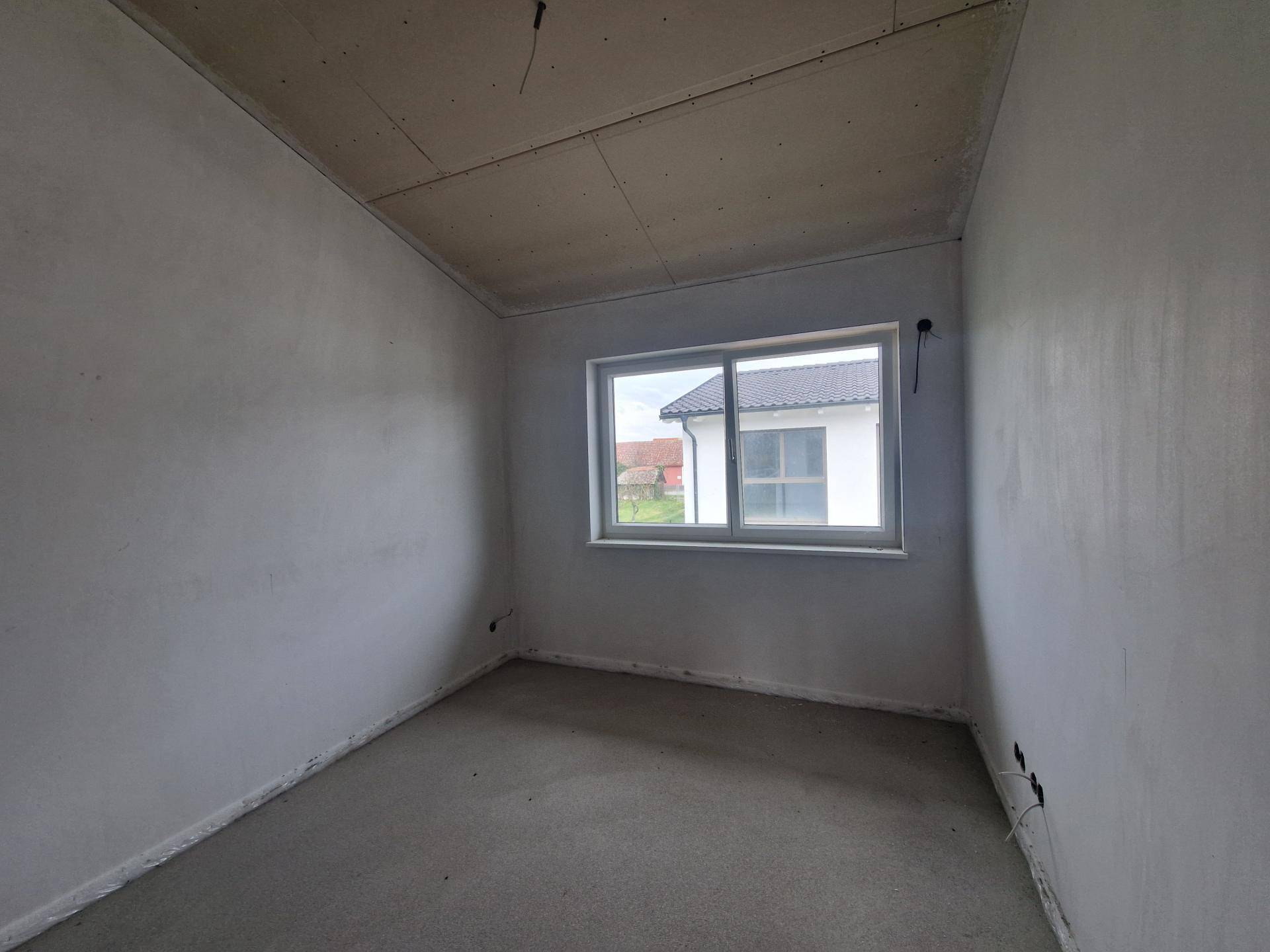 Rohbauzimmer mit einem Fenster, das einen Blick auf die Umgebung und ausreichend natürliches Licht bietet.