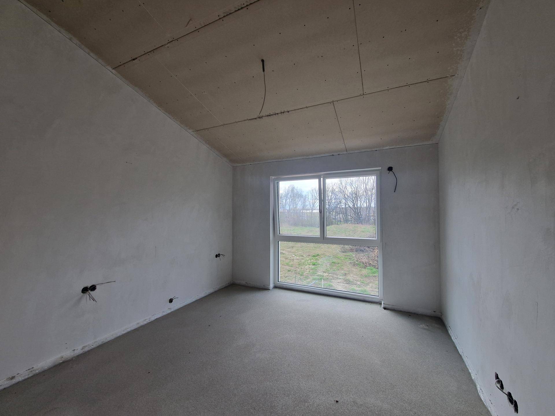 Rohbauzimmer mit einem großen Fenster, das viel Helligkeit spendet und eine weite Aussicht ermöglicht.
