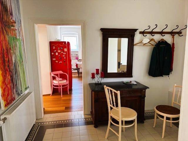 Eingangsbereich mit Fliesenboden, Garderobe, Spiegel und einem farbenfrohen Kunstwerk an der Wand.