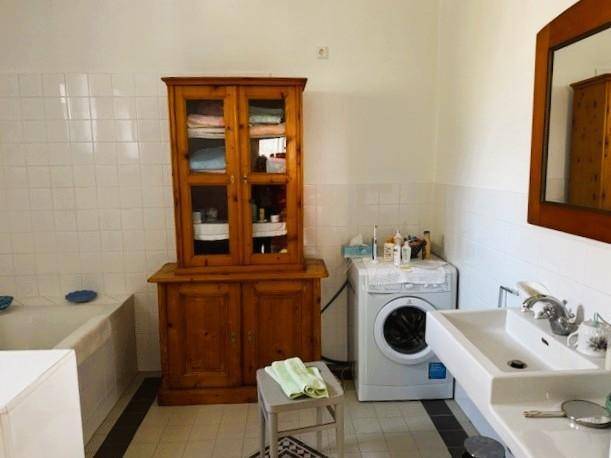 Funktionales Badezimmer mit Badewanne, Waschbecken, Waschmaschine und einem Holzschrank.