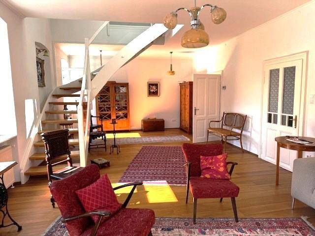Geräumiges Wohnzimmer mit Holztreppe, Parkettboden und traditionellen Möbeln in warmen Farbtönen.