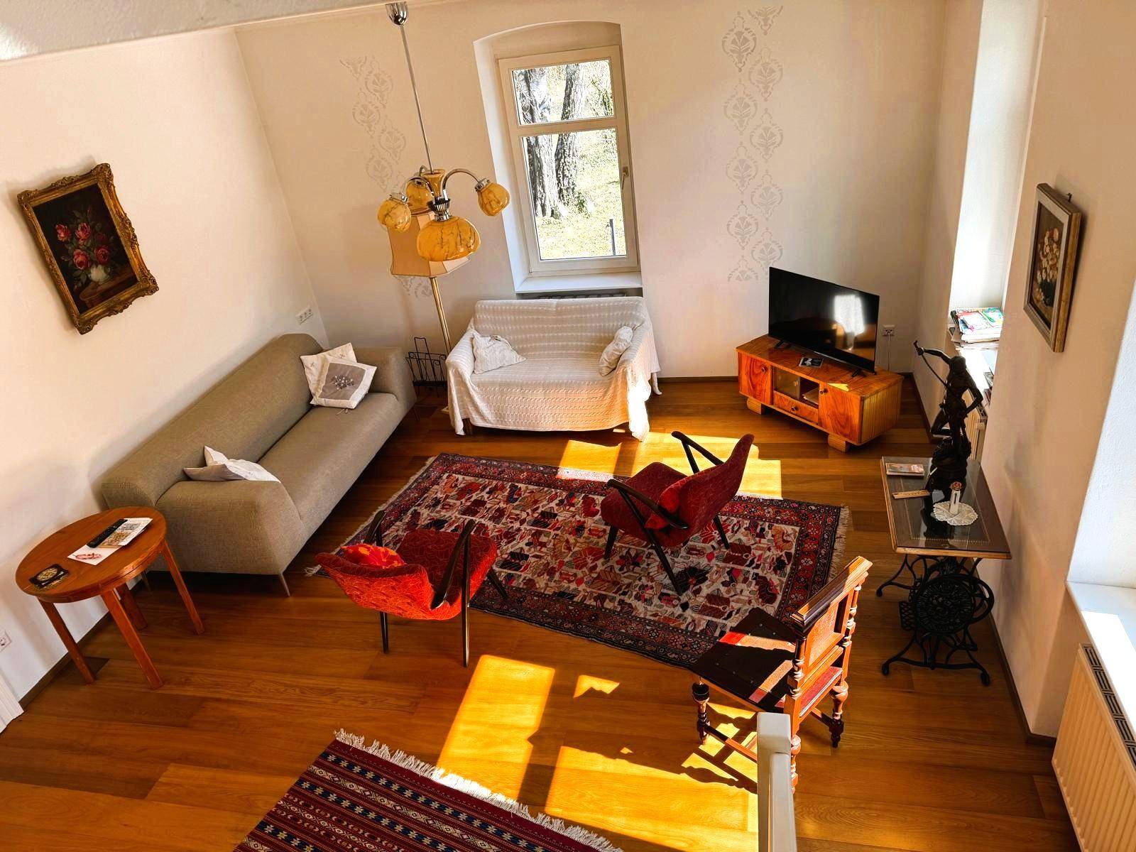Gemütliches Wohnzimmer mit Holzboden, zwei Sofas und einem Fenster mit Blick ins Grüne.