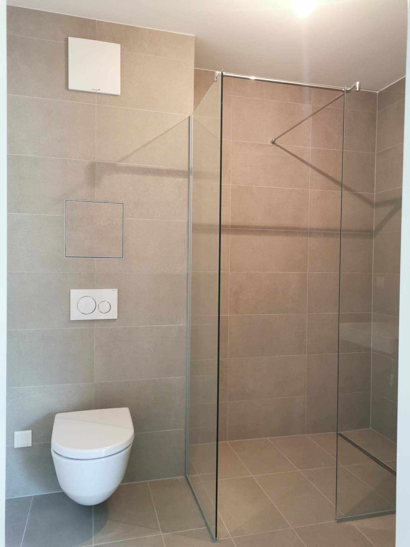 Modernes Badezimmer mit begehbarer Dusche, Wand-WC und großformatigen Fliesen.