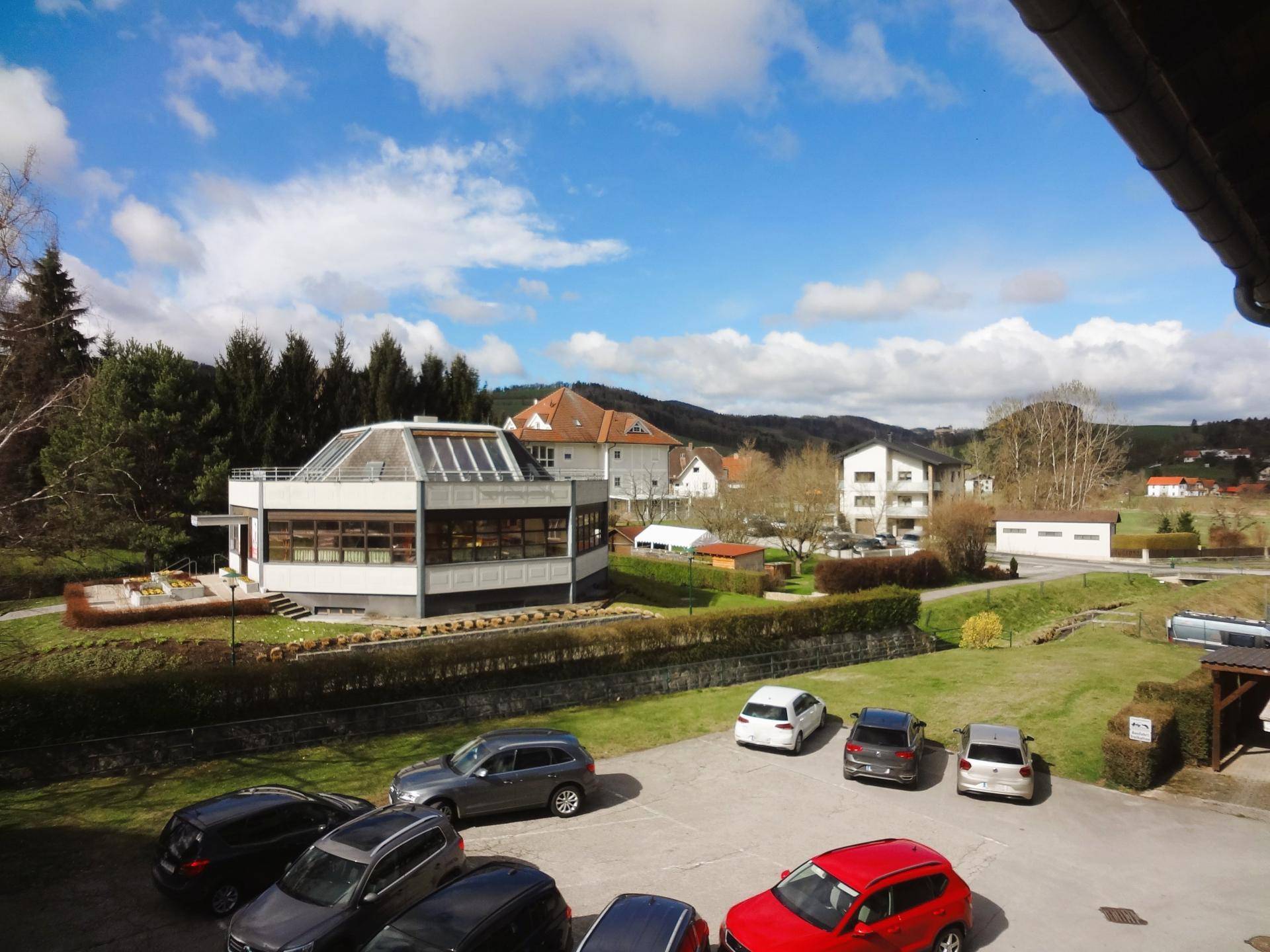 Weitläufige Umgebung mit Wohngebäuden, Grünflächen und Parkplätzen unter blauem Himmel.