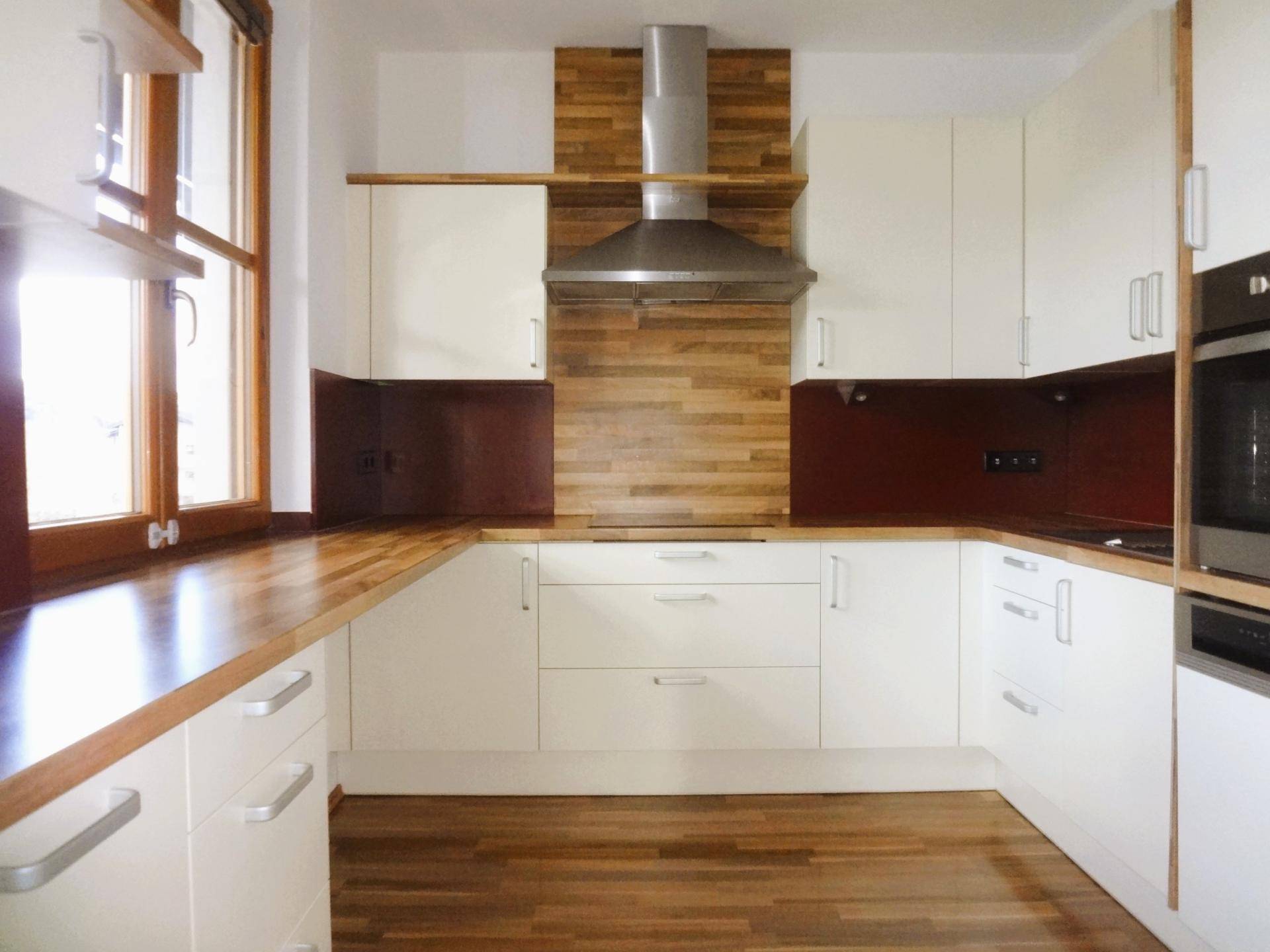 Funktionale Küche mit hellen Schränken, Holz-Arbeitsplatten und Dunstabzugshaube.