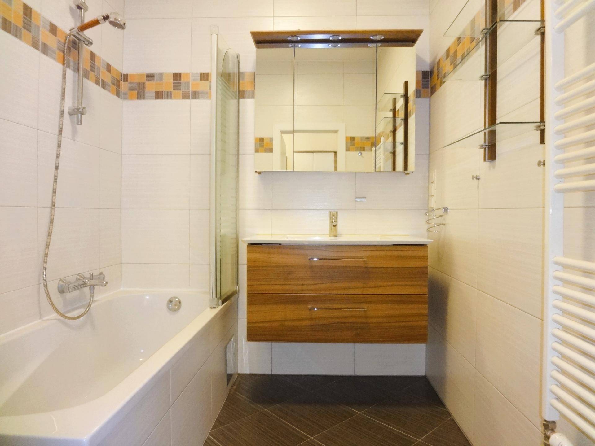 Badezimmer mit Badewanne, Duschfunktion, modernem Waschtisch und Handtuchheizkörper.