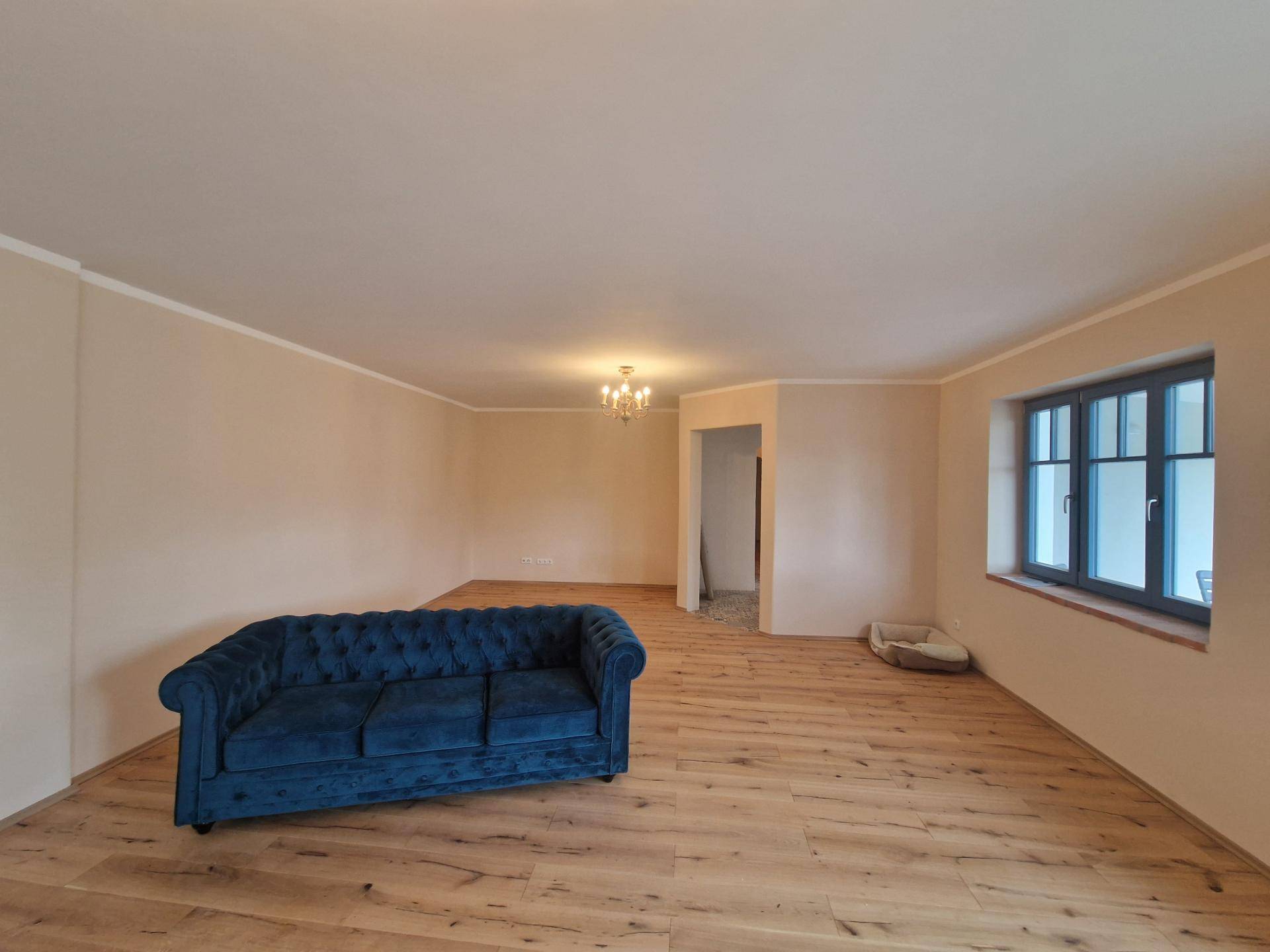 Helles Wohnzimmer mit Holzboden und einem blauen Sofa, ideal für Entspannung.
