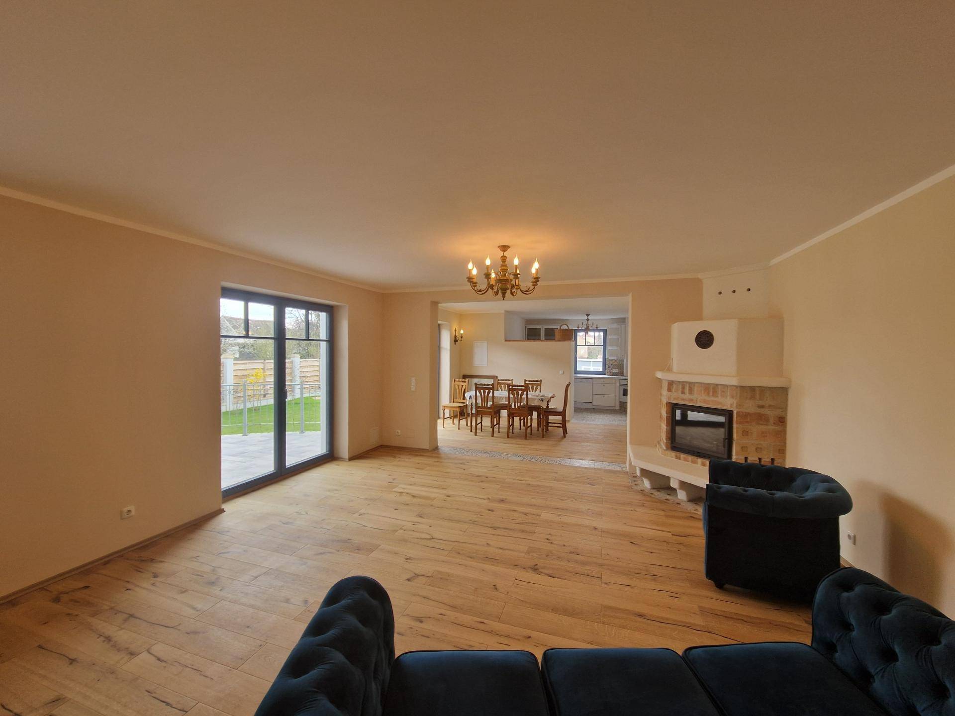 Geräumiges Wohnzimmer mit Holzboden, Kamin und Zugang zu einem Essbereich.