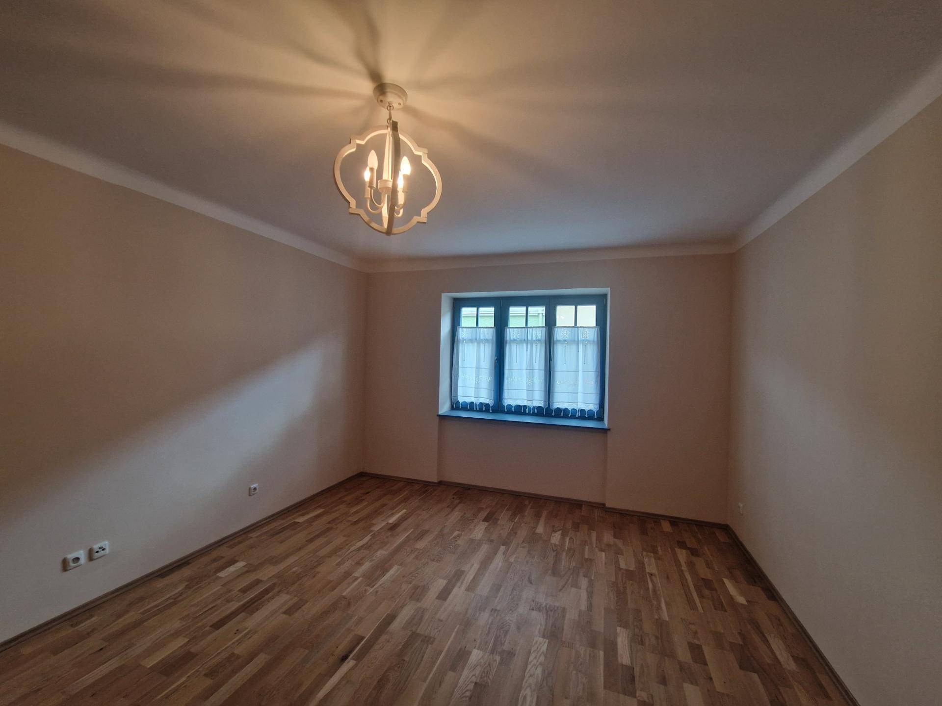Leerer Raum mit Holzboden und Fenster, vielseitig nutzbar.