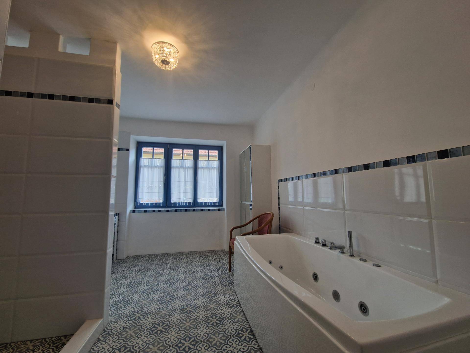 Geräumiges Badezimmer mit Whirlpool-Badewanne und gemusterten Bodenfliesen.
