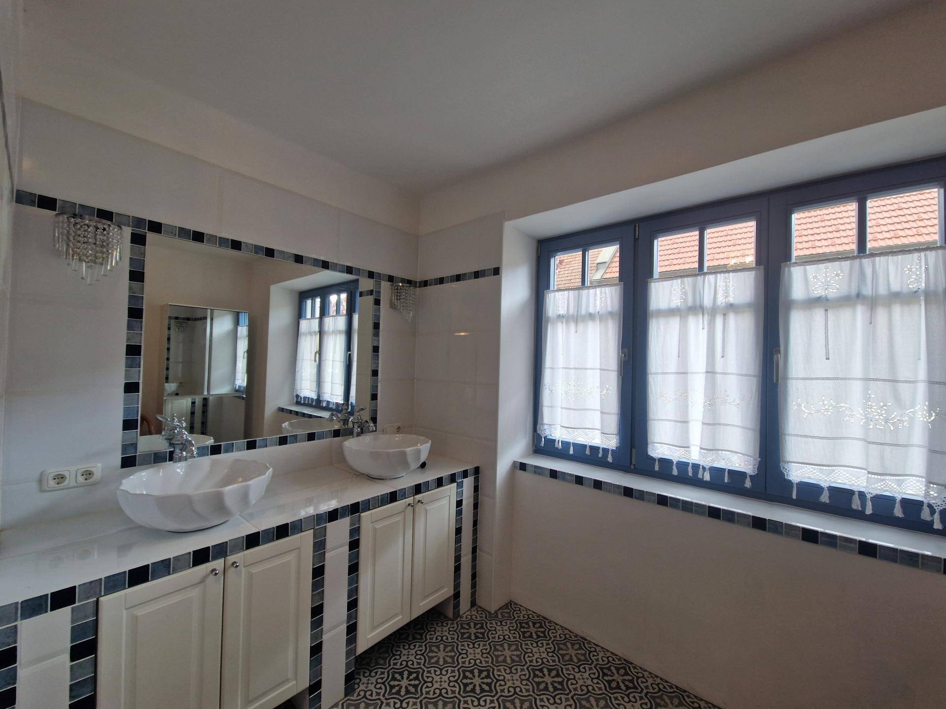 Modernes Badezimmer mit Doppelwaschbecken, großem Spiegel und gemusterten Fliesen.