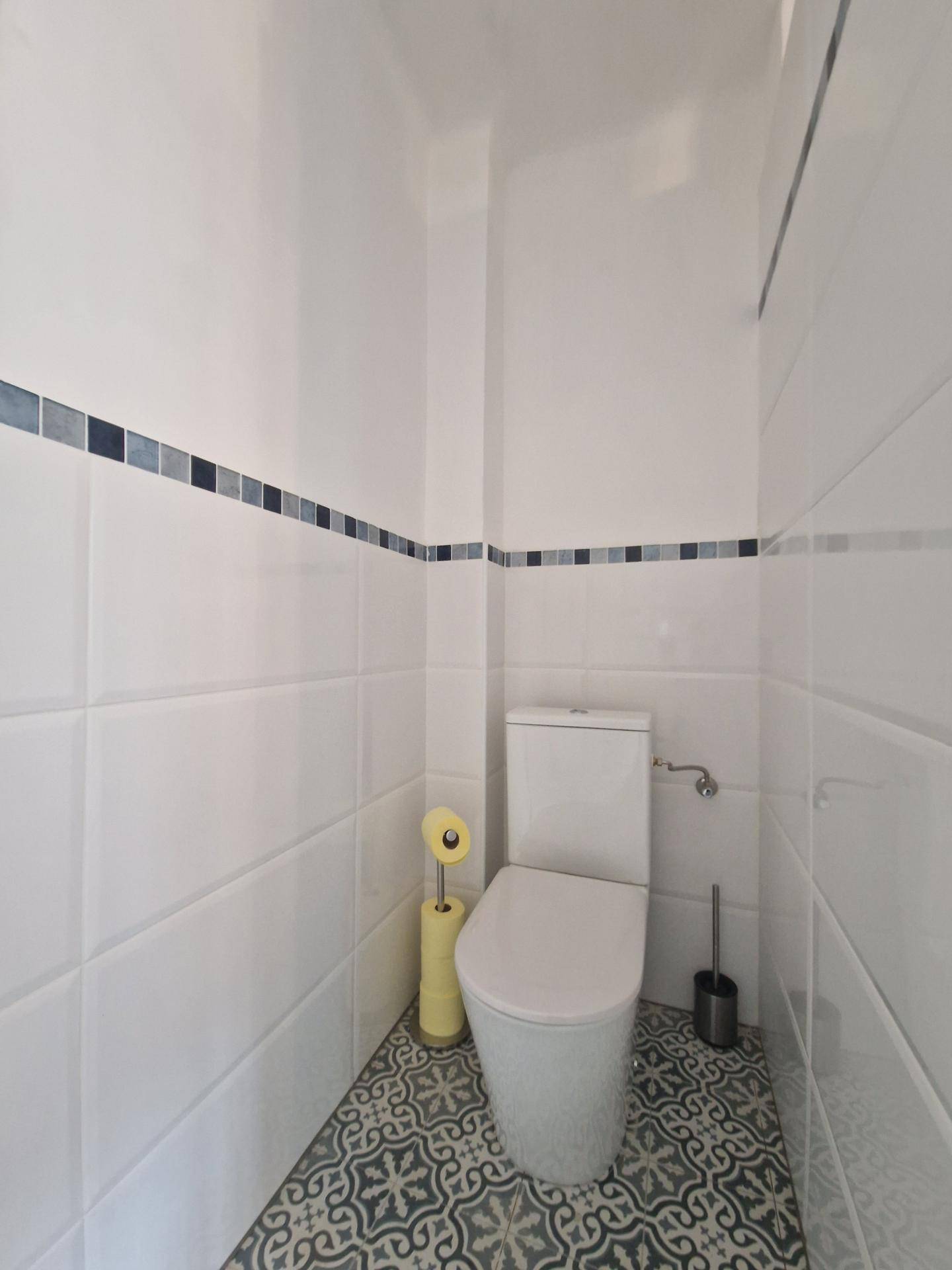 Separates WC mit modernen Fliesen und einfacher Ausstattung.