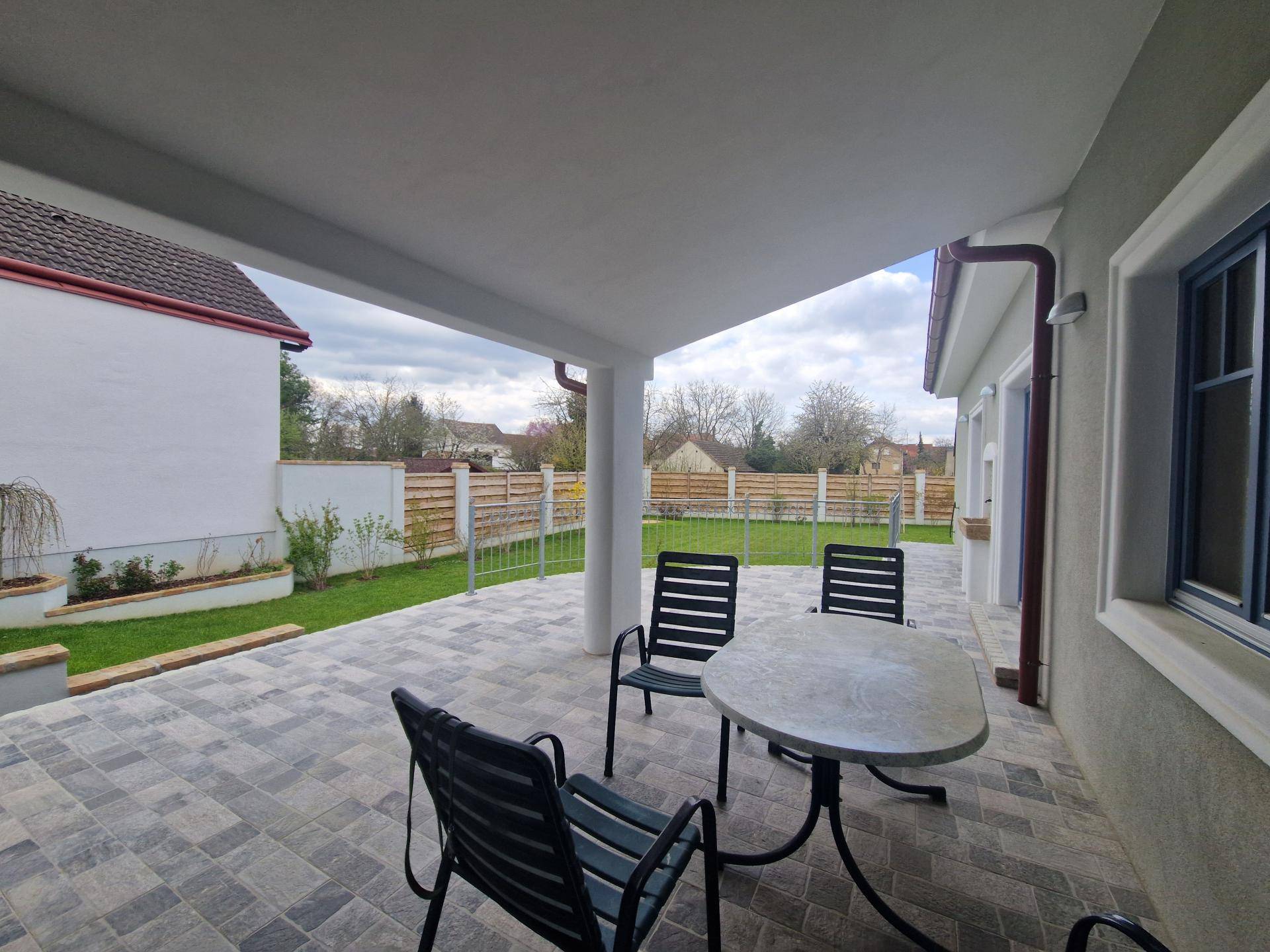 Überdachte Terrasse mit Sitzgelegenheiten und Blick auf den gepflegten Garten.