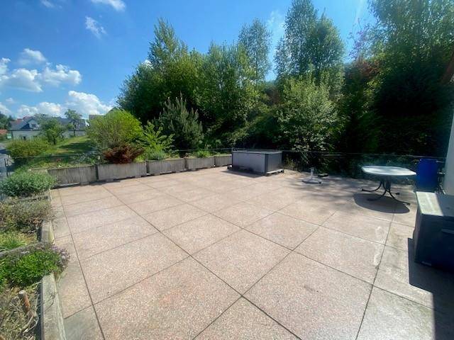Weitläufige gepflasterte Terrasse mit Whirlpool und viel Grün, ideal zum Entspannen im Freien.
