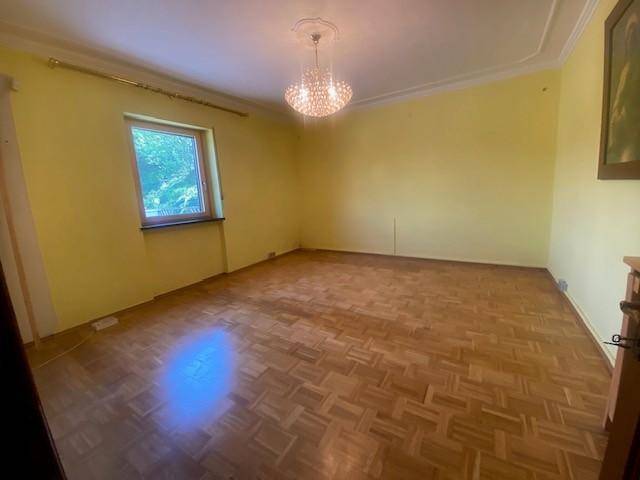 Helles Schlafzimmer mit gelben Wänden, Parkettboden und einem Fenster, bereit zur Einrichtung.