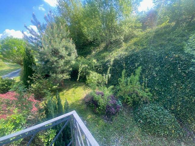 Blick von einem Balkon auf einen üppigen, grünen Garten mit vielfältiger Bepflanzung.