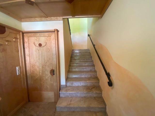 Marmortreppe mit Handlauf führt in die obere Etage, umgeben von Holzelementen.