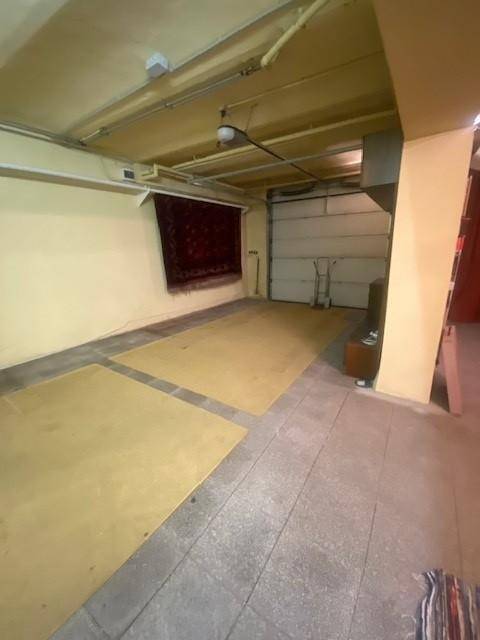 Große Garage mit Betonboden und einem Rolltor, ideal für Fahrzeuge oder als Abstellraum.