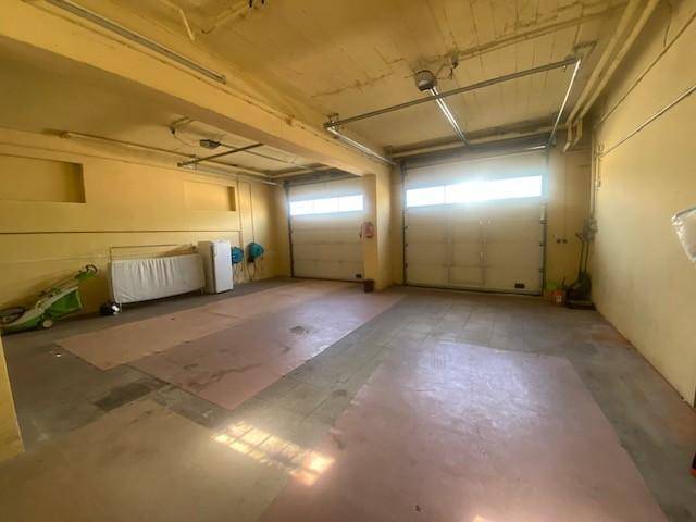 Geräumige Garage mit zwei Rolltoren und viel Platz für Fahrzeuge oder Lagerung.