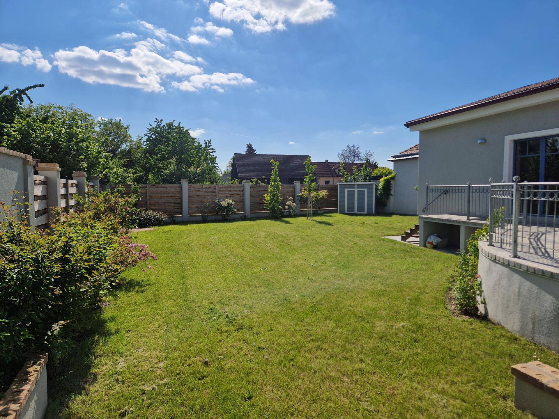 Weitläufiger Garten mit Rasenfläche und Zugang zu einer kleinen Terrasse am Haus.