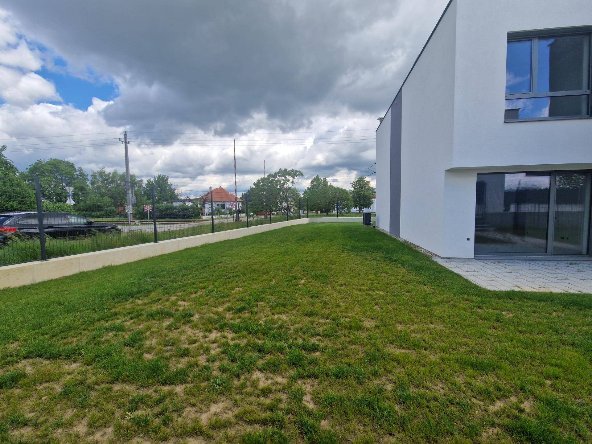 Seitlicher Rasenbereich neben dem Haus mit Blick auf die Straße und die Nachbarschaft.