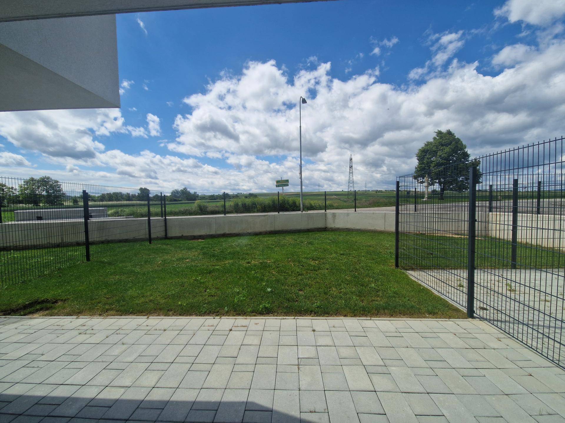 Gepflegter Rasenbereich mit Zaun und freiem Blick auf die weite, grüne Landschaft.