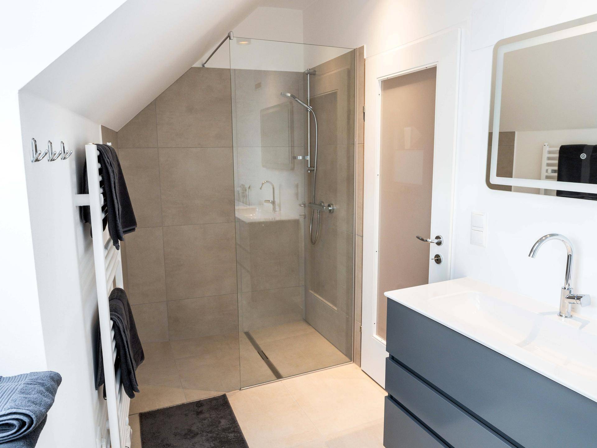 Modernes Badezimmer mit ebenerdiger Dusche, Waschbeckenunterschrank und schrägen Wänden im Dachgeschoss.
