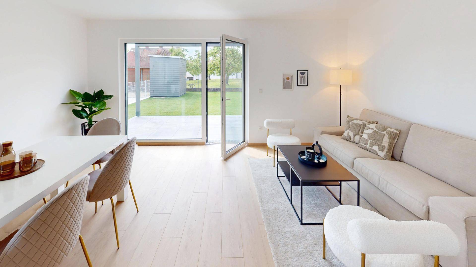 Gemütlicher Wohnbereich mit Sofa und Esstisch, großen Fenstern und direktem Zugang zum Garten.
