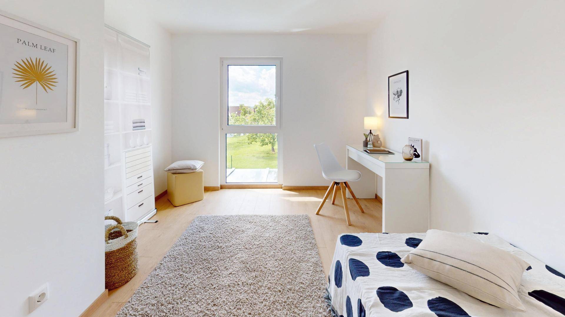 Helles Schlafzimmer mit Einzelbett, Schreibtisch und großem Fenster mit Blick ins Grüne.