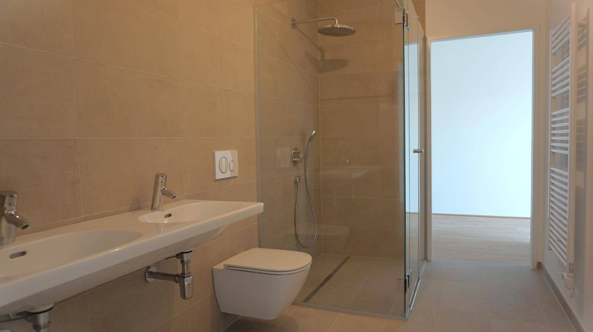 Modernes Badezimmer mit doppelten Waschbecken, wandhängendem WC und einer ebenerdigen Dusche.