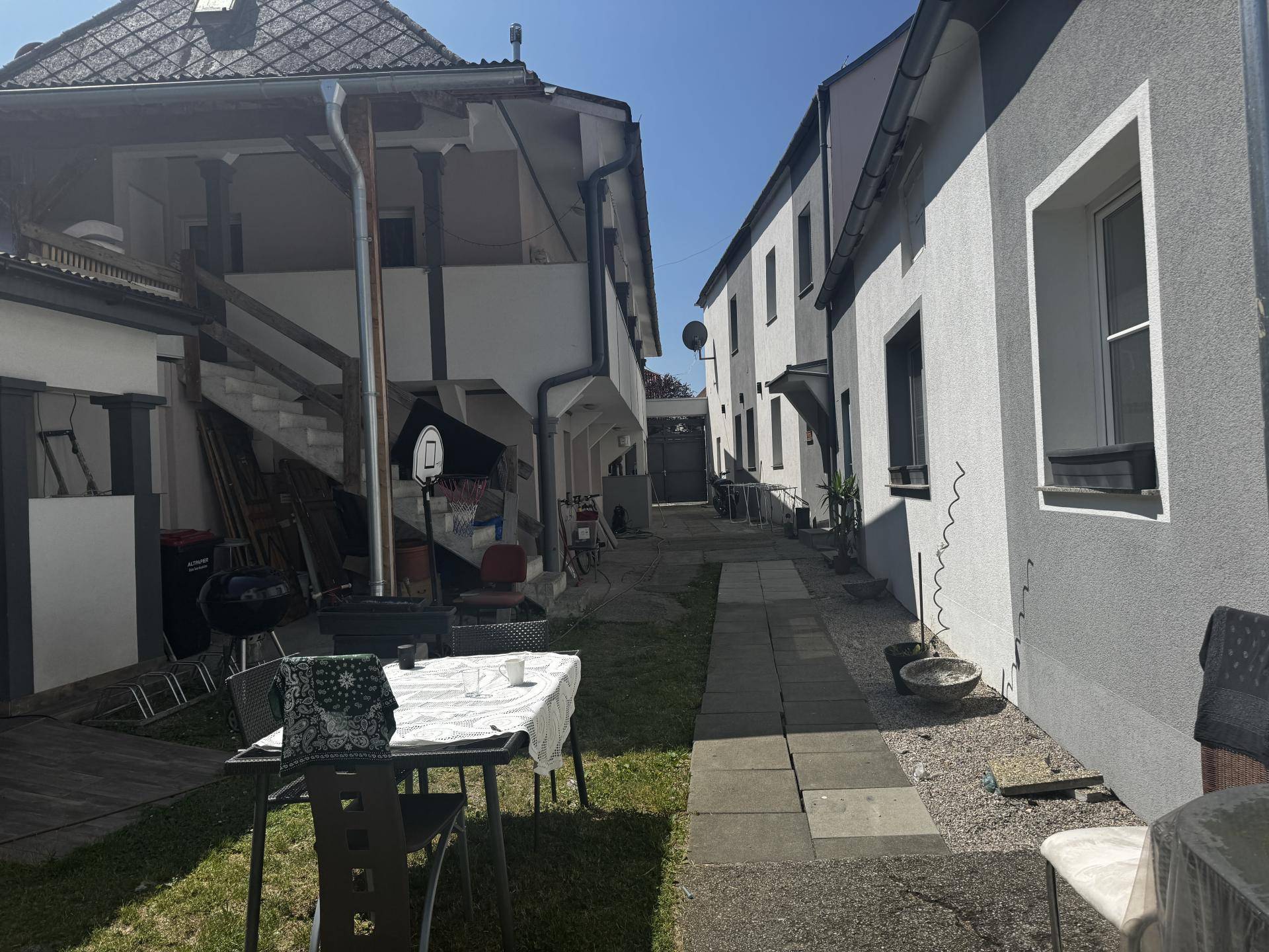Gartenbereich mit einem Esstisch im Freien und Blick auf die umliegenden Gebäude.