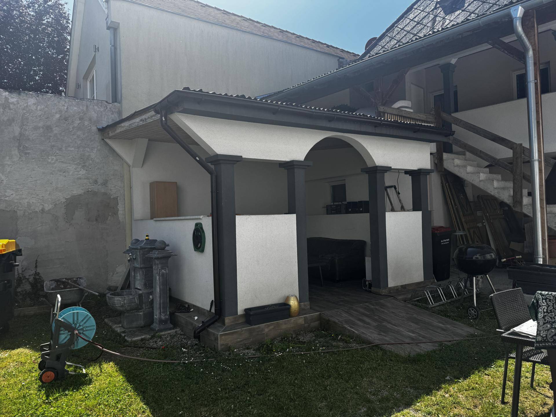 Überdachte Terrasse mit Säulen und einem Holzboden, ideal für entspannte Stunden im Freien.