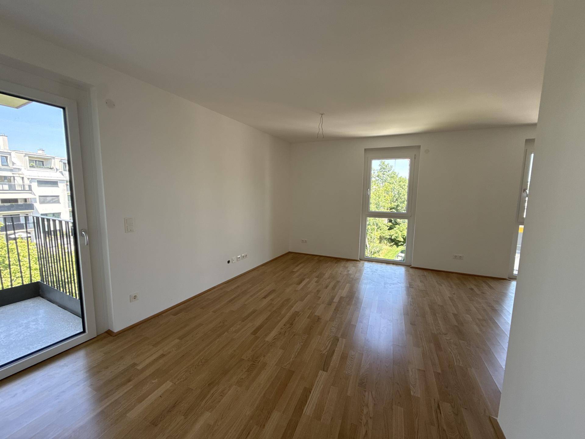 Geräumiges, helles Zimmer mit Holzboden und direktem Zugang zu einem Balkon.