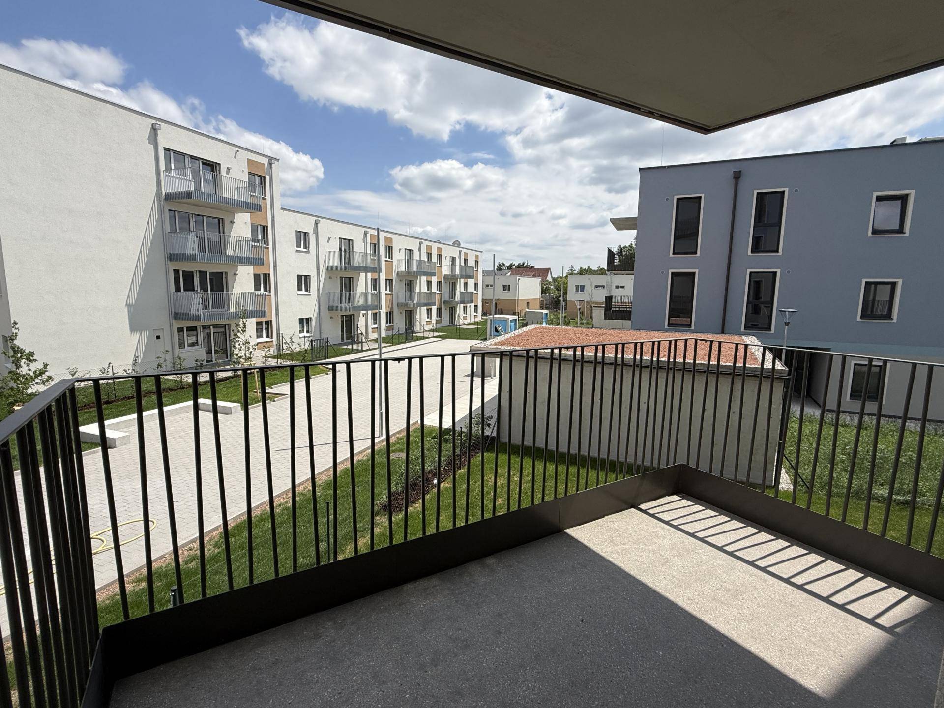 Balkon mit Metallgeländer und Blick auf die gepflegte Grünanlage und moderne Wohngebäude.