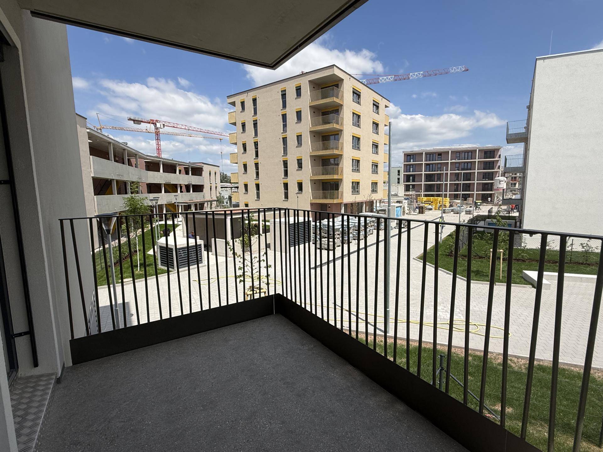 Balkon mit weitem Blick auf die umliegende Neubausiedlung und Baukräne am Horizont.
