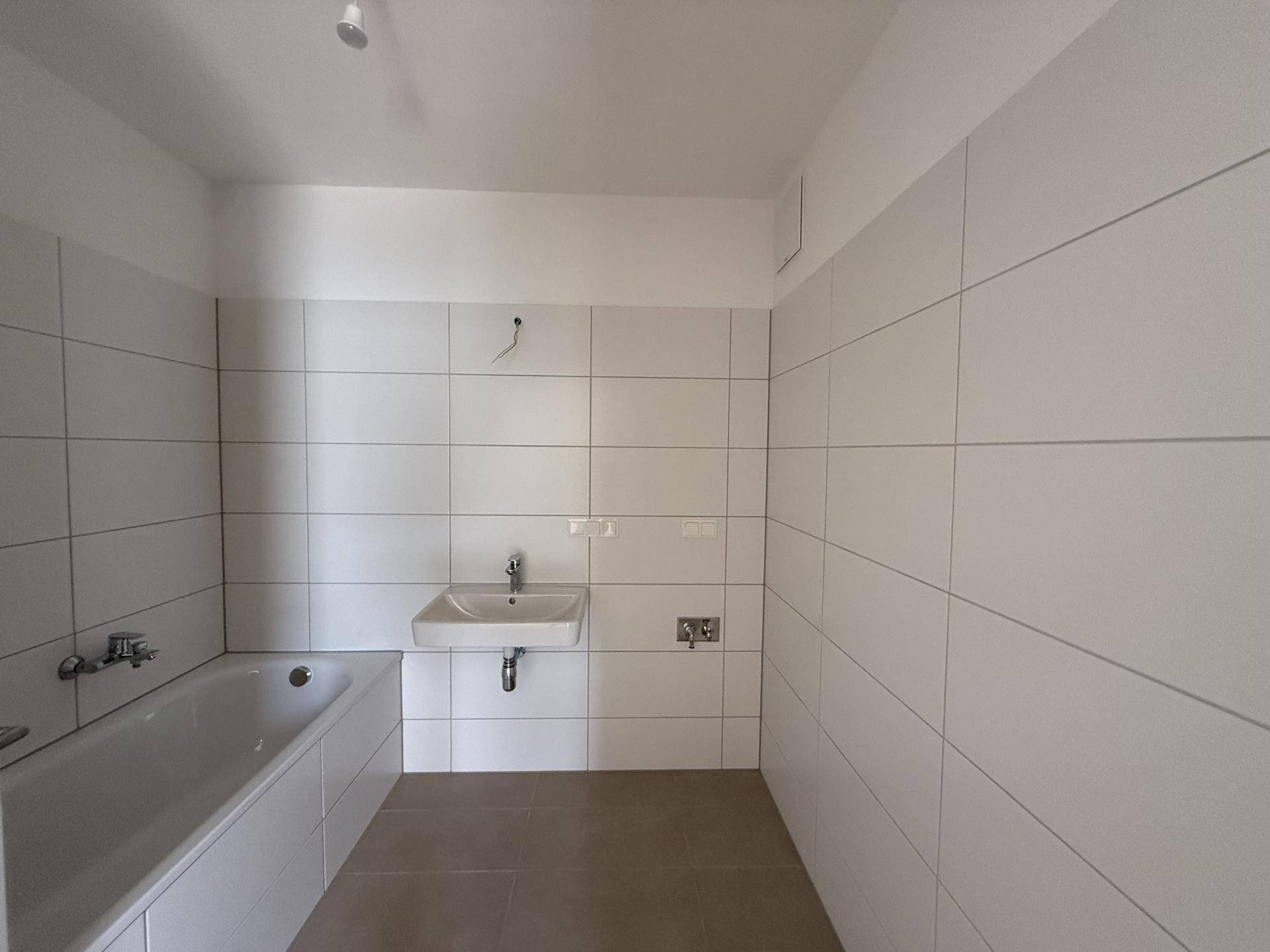 Modernes Badezimmer mit weißen Wandfliesen, Badewanne und einem einzelnen Waschbecken.