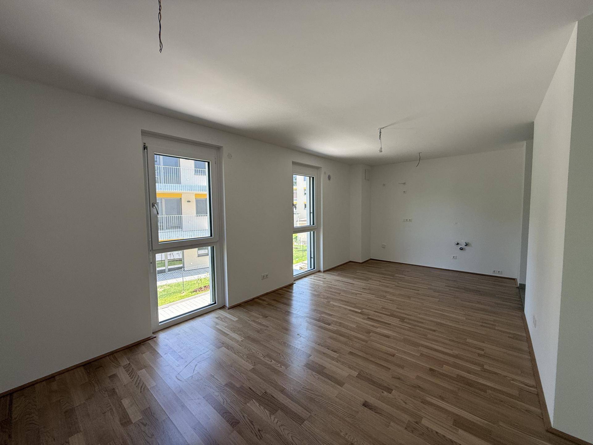 Geräumiger, heller Wohnraum mit Parkettboden und zwei großen Fenstern mit Blick auf den Innenhof.