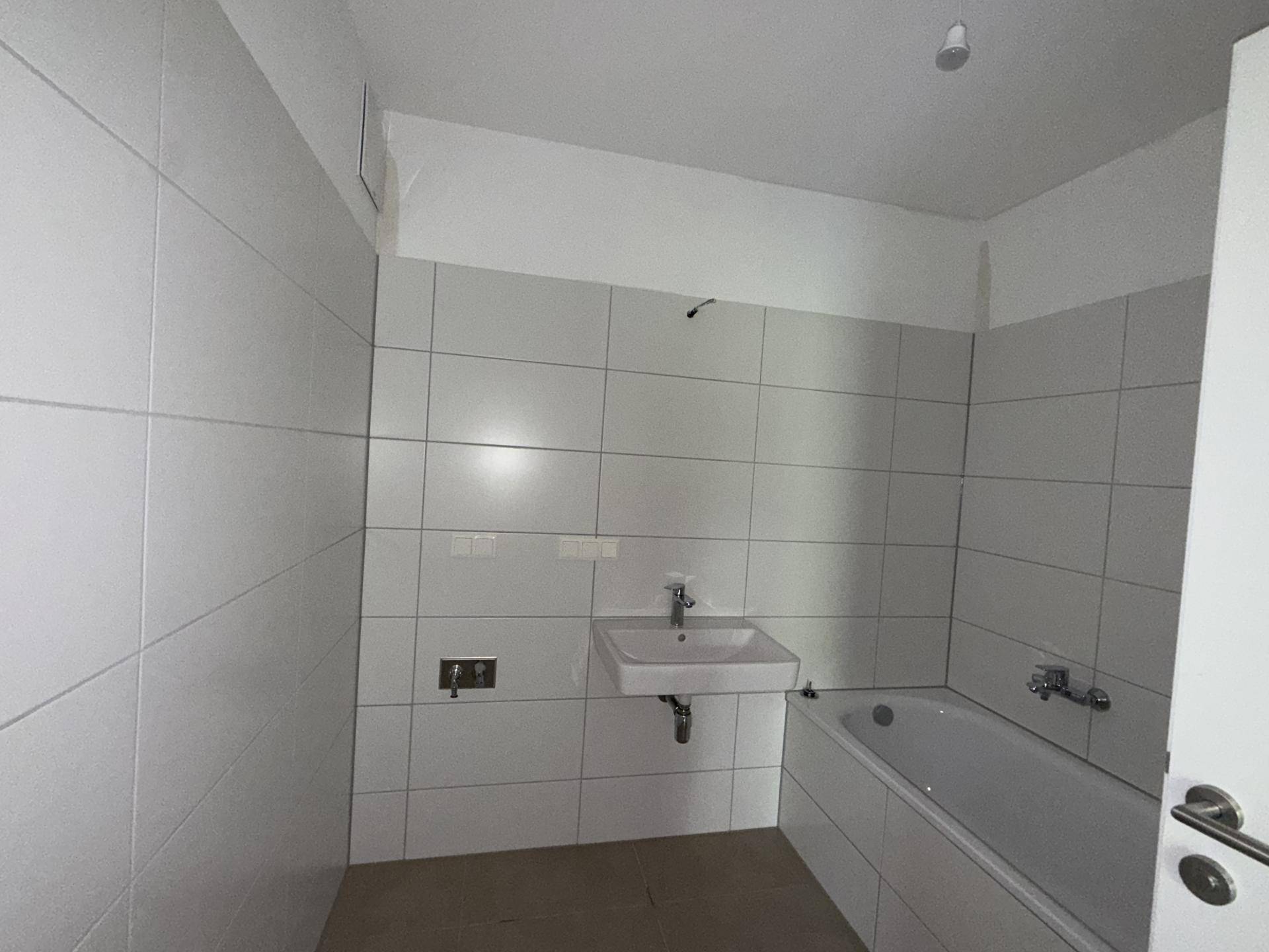 Modernes Badezimmer mit weißen Fliesen, Waschbecken und einer Badewanne.