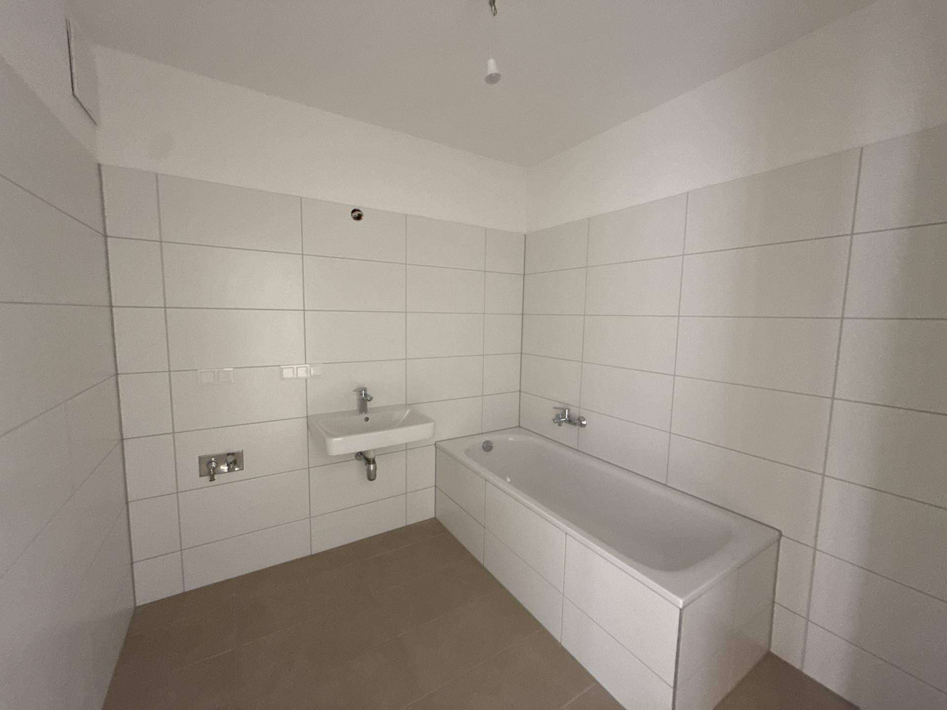 Modernes Badezimmer mit weißen Wandfliesen, einer Badewanne und einem Waschbecken.