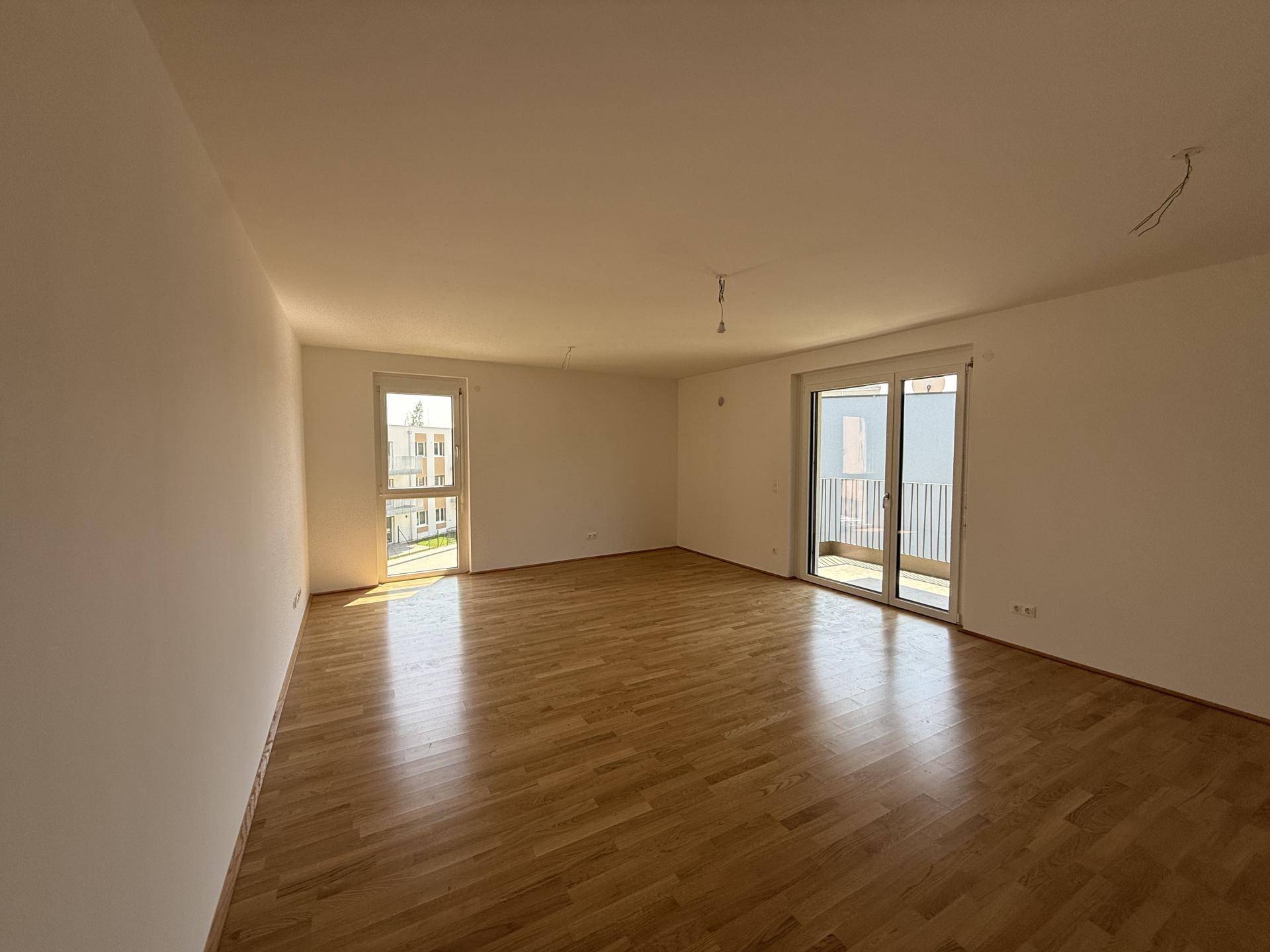 Geräumiges, helles Zimmer mit Holzboden und zwei Fenstern, eines davon mit französischem Balkon.