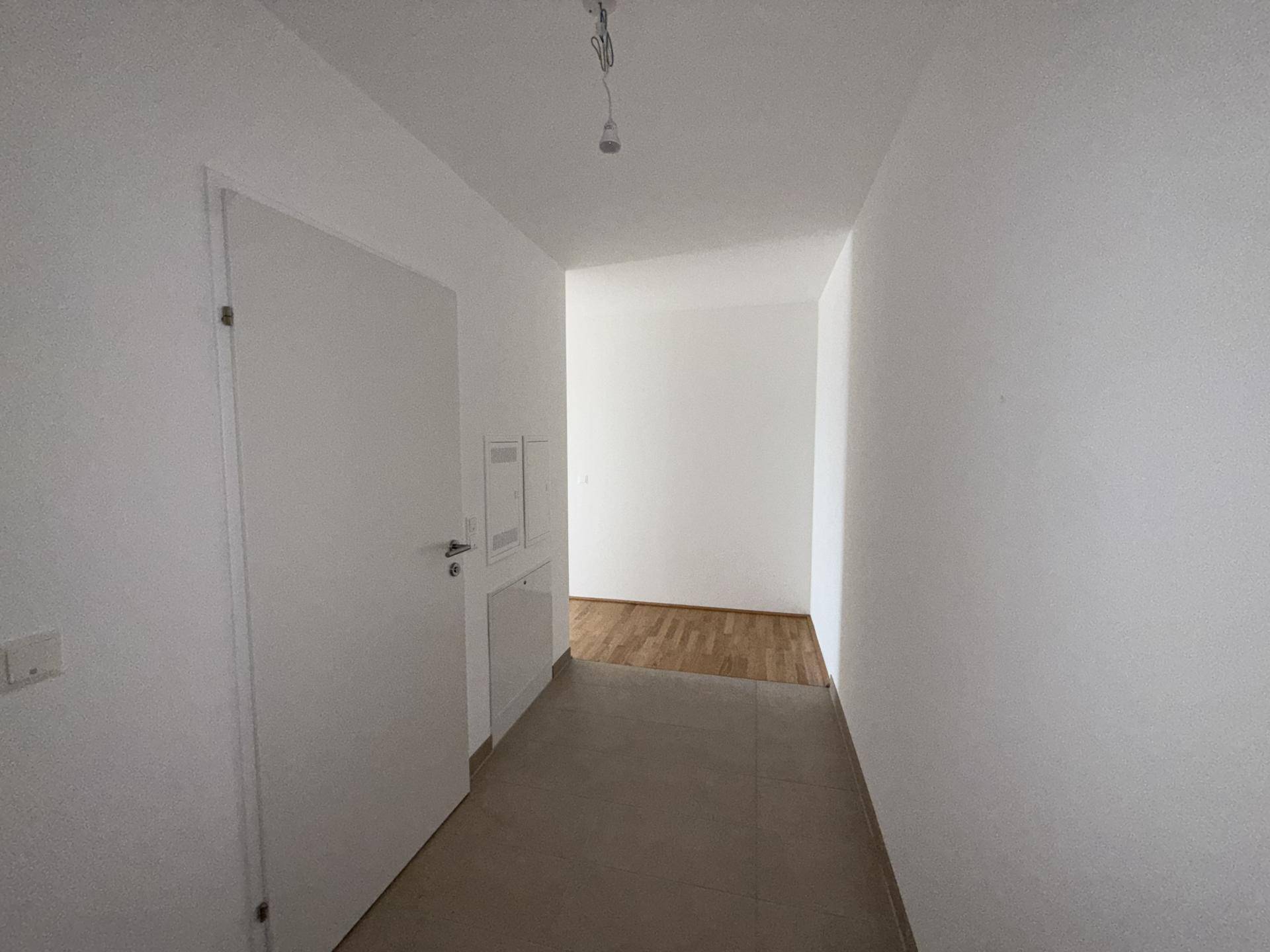 Eingangsbereich mit Fliesenboden und weißer Tür, der zu den Wohnräumen führt.