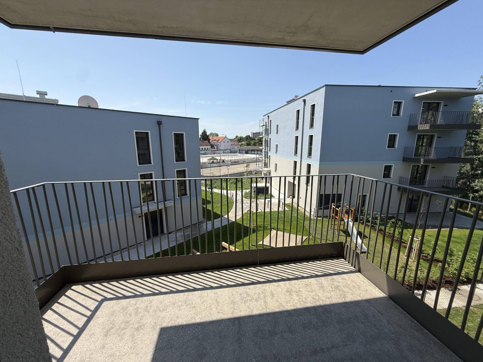 Balkon mit Blick auf den Innenhof und moderne Wohngebäude in der Umgebung.