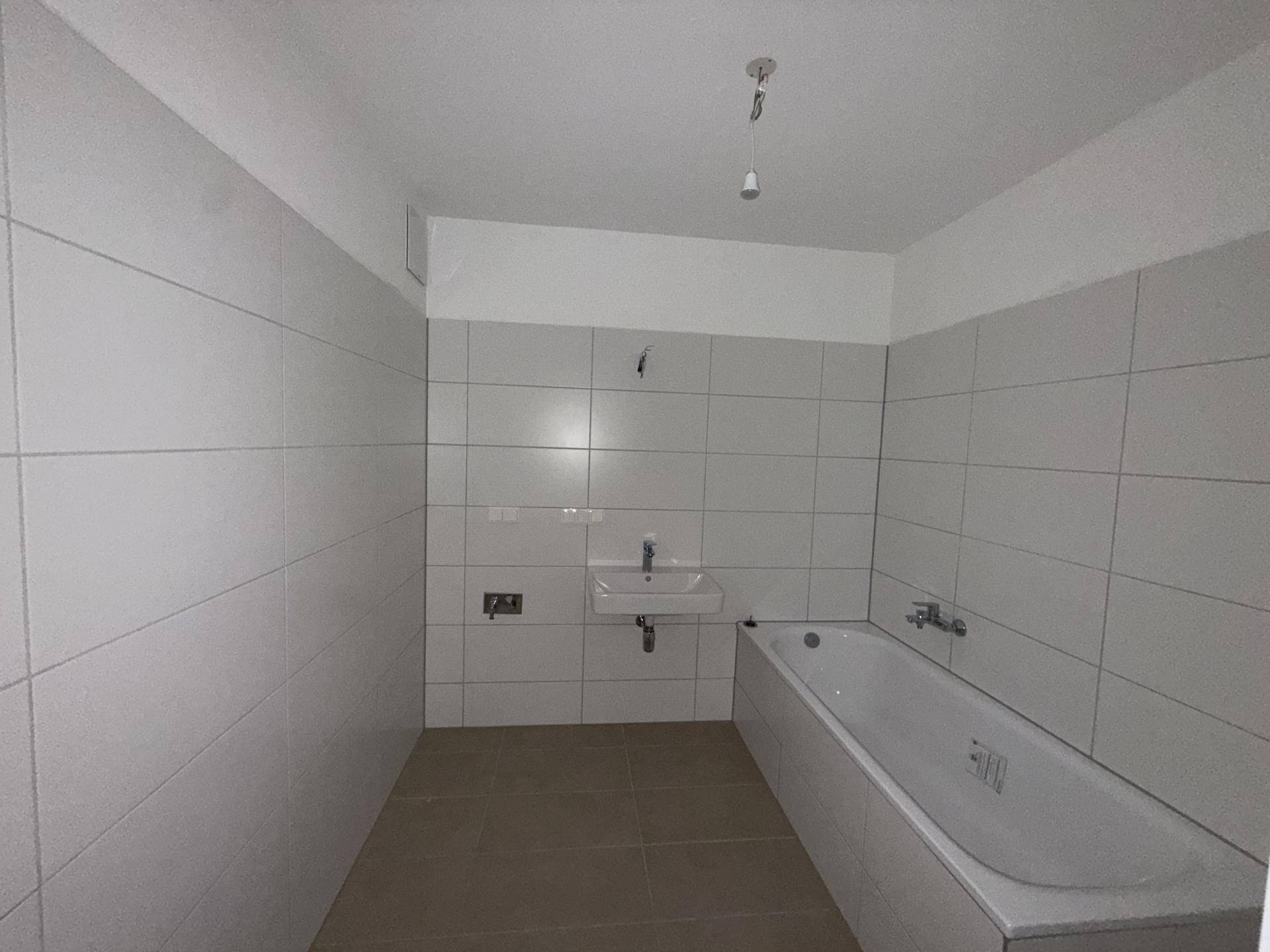Modernes Badezimmer mit weißen Fliesen, Badewanne und Waschbecken.
