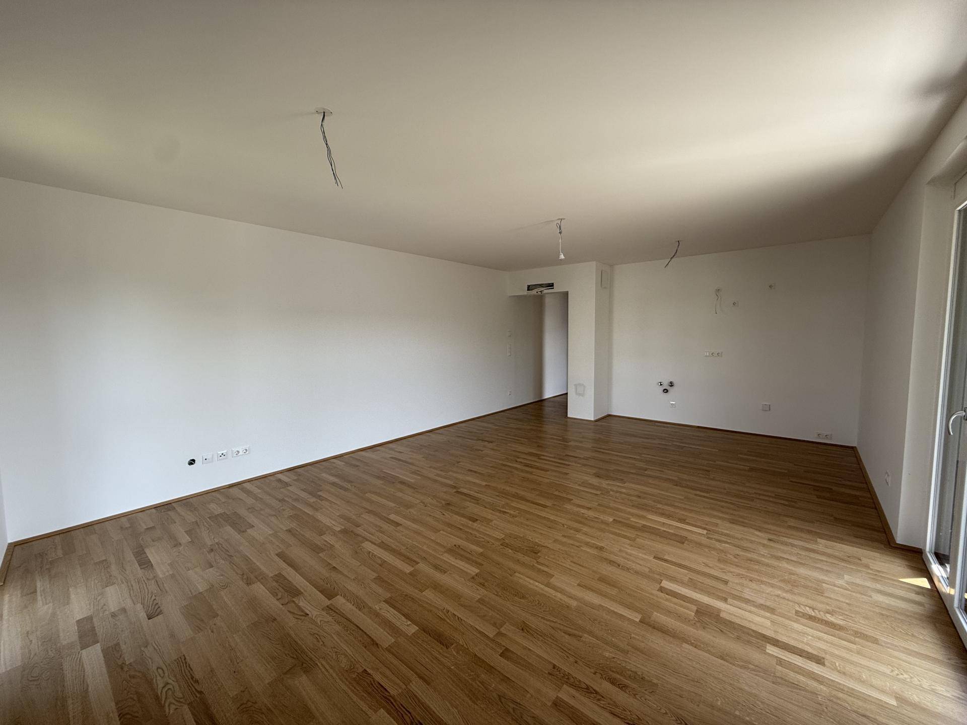 Geräumiges, leeres Wohnzimmer mit Holzboden und viel Potenzial für individuelle Gestaltung.