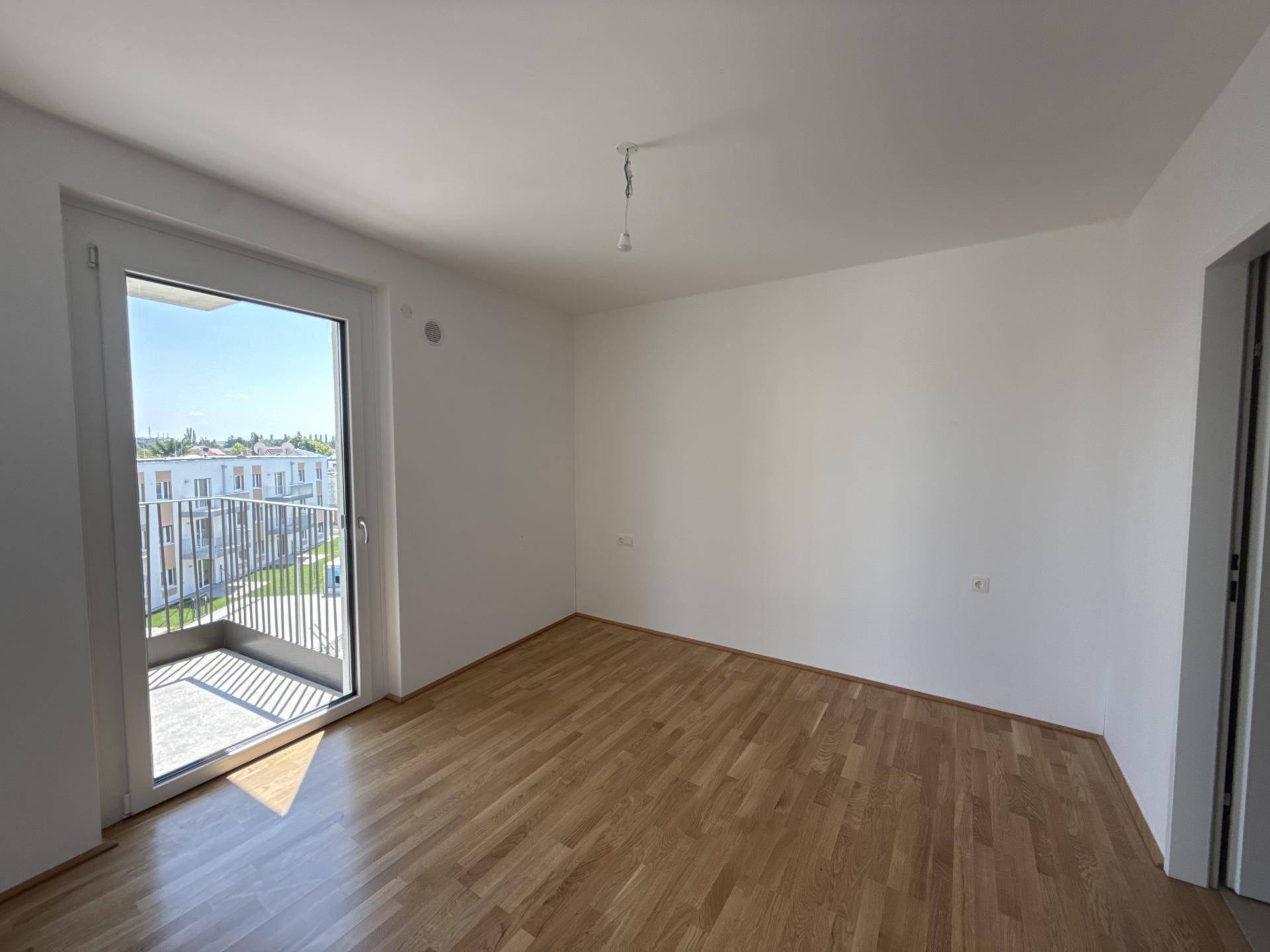 Helles Schlafzimmer mit Parkettboden und direktem Zugang zu einem privaten Balkon.