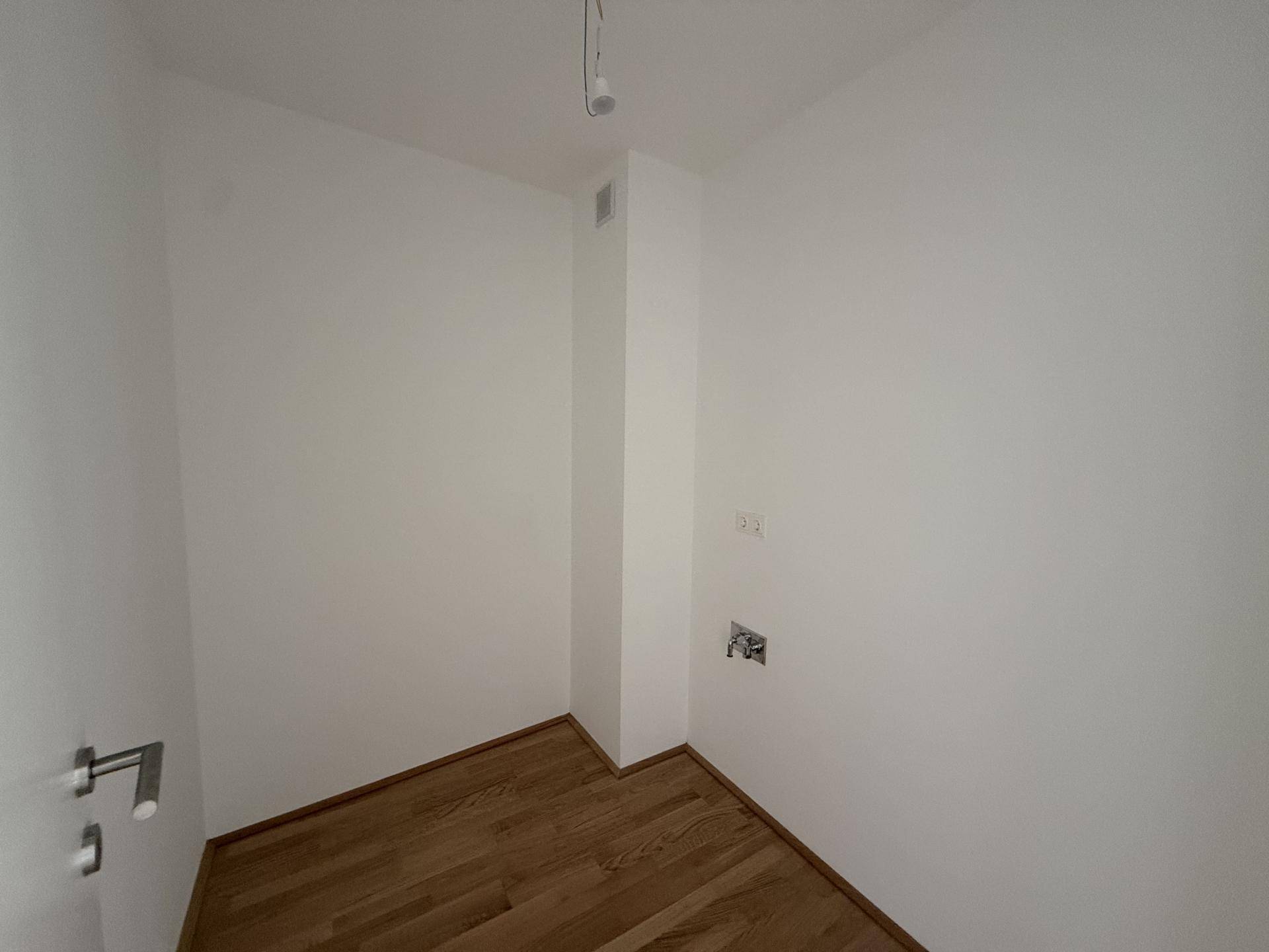 Kleiner Raum mit Parkettboden und Anschlüssen, ideal als Abstell- oder Hauswirtschaftsraum.