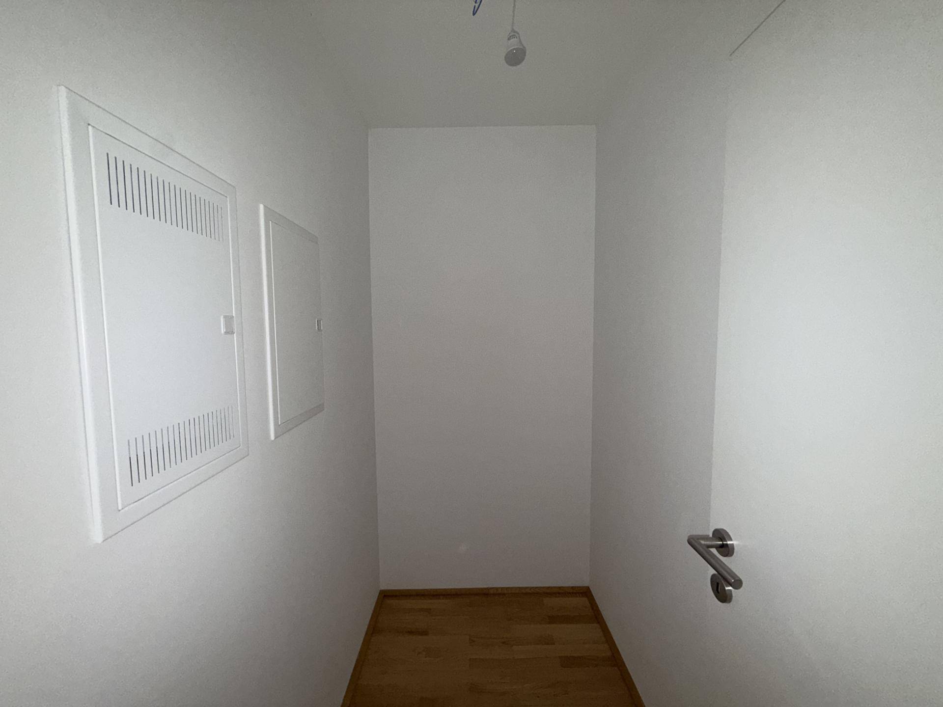 Kleiner Abstellraum mit Holzboden und Zugang zu den technischen Installationen des Hauses.